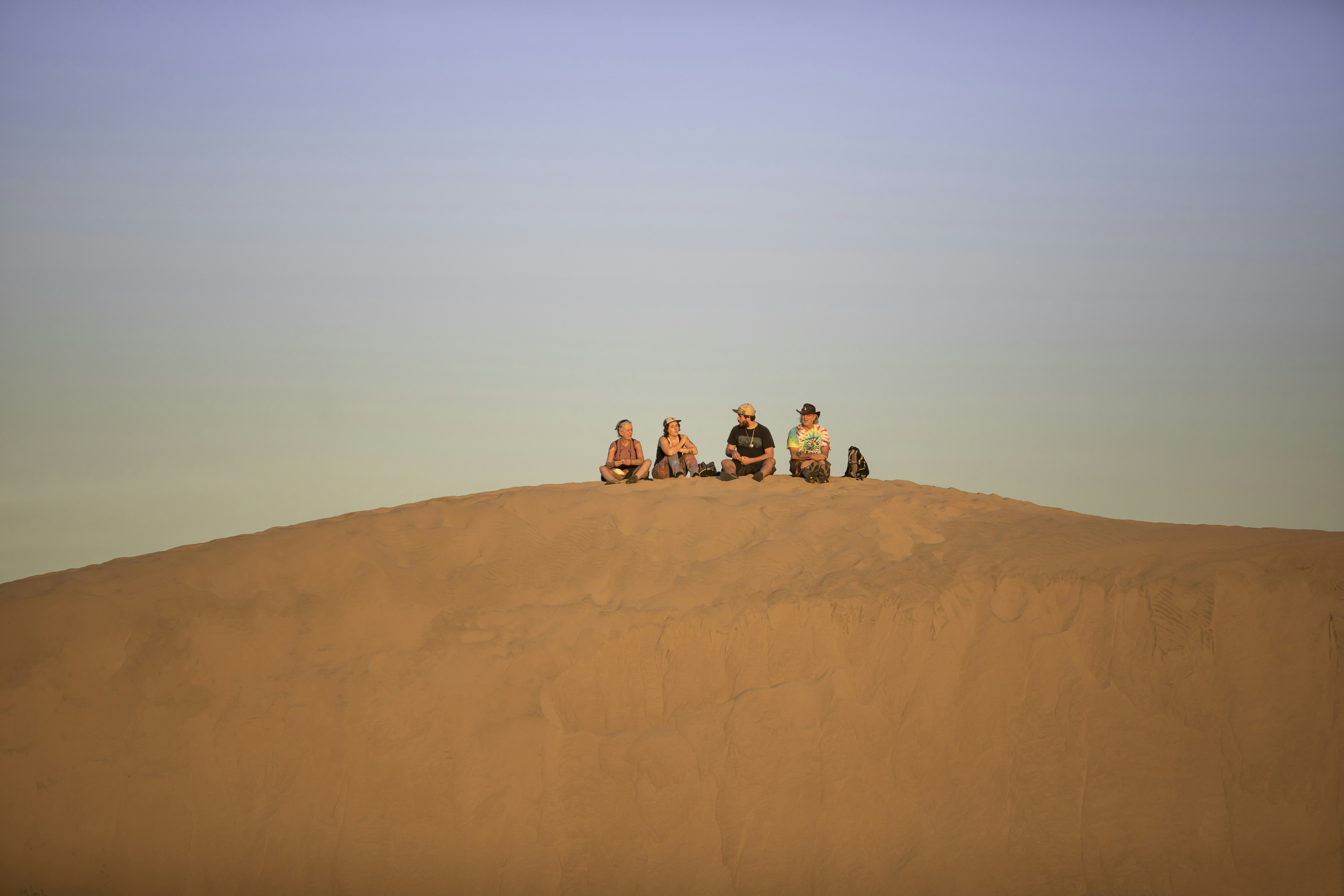 a group of people sitting on a sand dune
